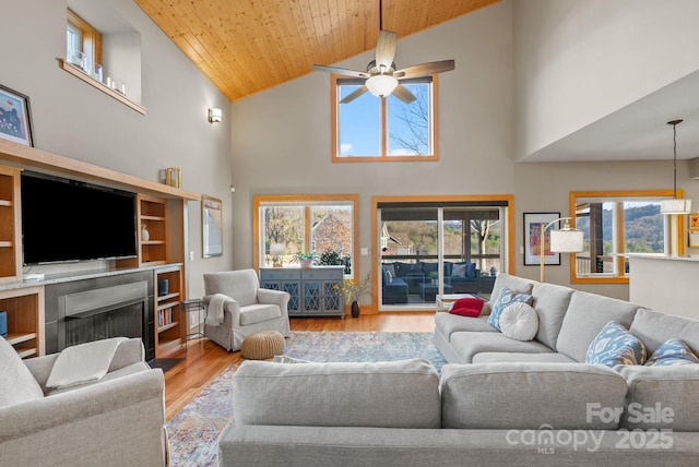 living room featuring ceiling fan, a wealth of natural light, light hardwood / wood-style floors, and wooden ceiling