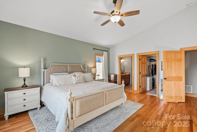 bedroom featuring lofted ceiling, light hardwood / wood-style flooring, ceiling fan, a walk in closet, and a closet