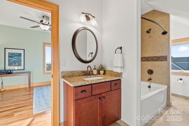 bathroom with vanity, tiled shower / bath combo, wood-type flooring, and ceiling fan