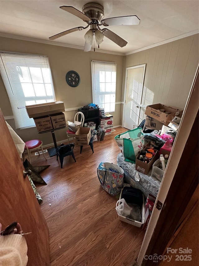 interior space featuring ceiling fan, wood-type flooring, and crown molding