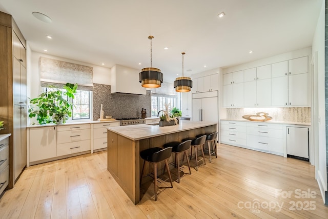 kitchen featuring white cabinetry, a center island, paneled built in refrigerator, and decorative light fixtures