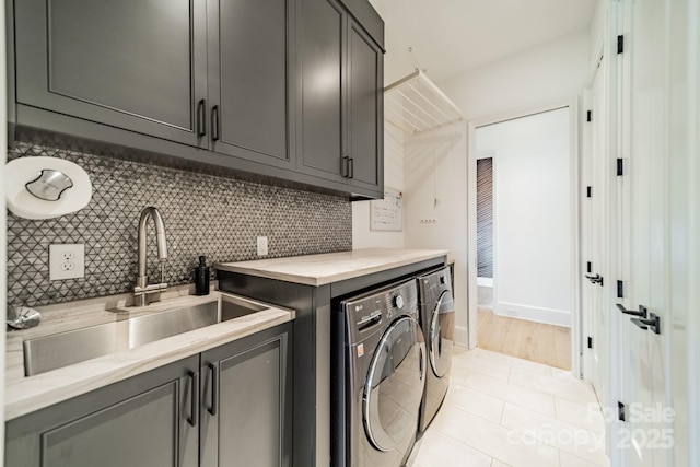 laundry room with sink, cabinets, washing machine and clothes dryer, and light tile patterned flooring