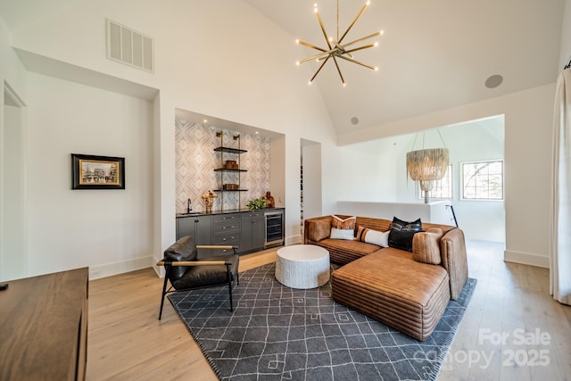 living room with sink, a chandelier, high vaulted ceiling, hardwood / wood-style flooring, and beverage cooler