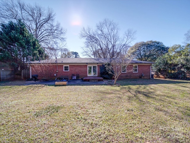 back of property featuring a hot tub, a wooden deck, and a lawn