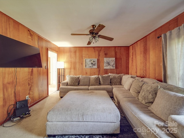 living room with light colored carpet, ceiling fan, and wood walls