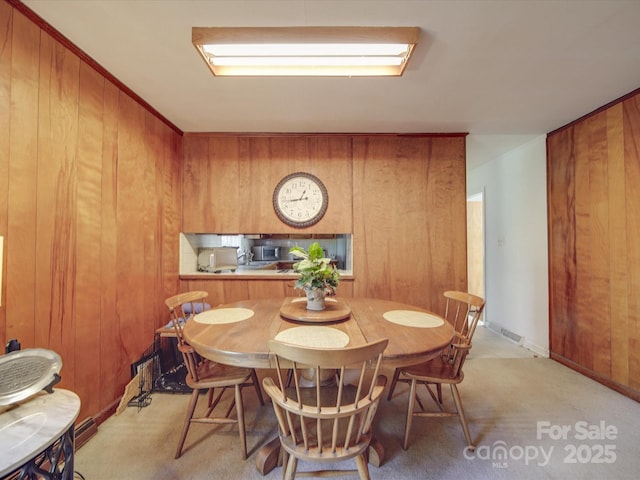 carpeted dining space with wood walls