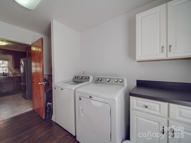 laundry area with washer and dryer, dark hardwood / wood-style flooring, and cabinets