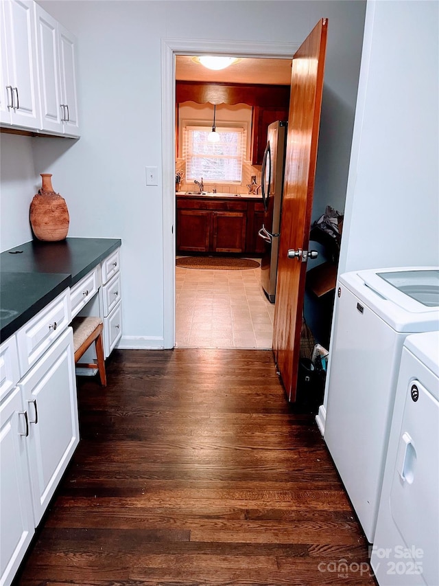 clothes washing area featuring washer and dryer, dark hardwood / wood-style floors, and cabinets