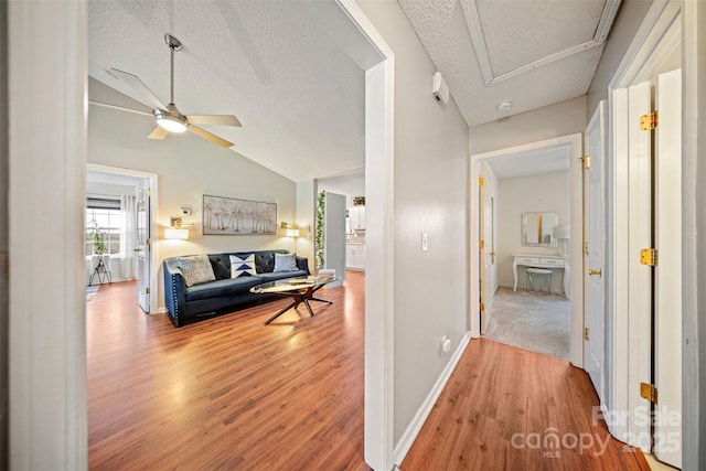 hallway featuring hardwood / wood-style floors, a textured ceiling, and lofted ceiling