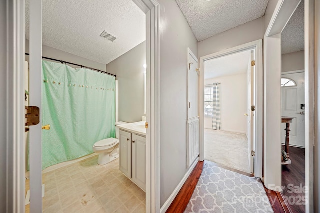 bathroom with vanity, toilet, and a textured ceiling