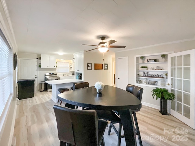 dining space featuring light wood-type flooring, built in features, ceiling fan, and ornamental molding