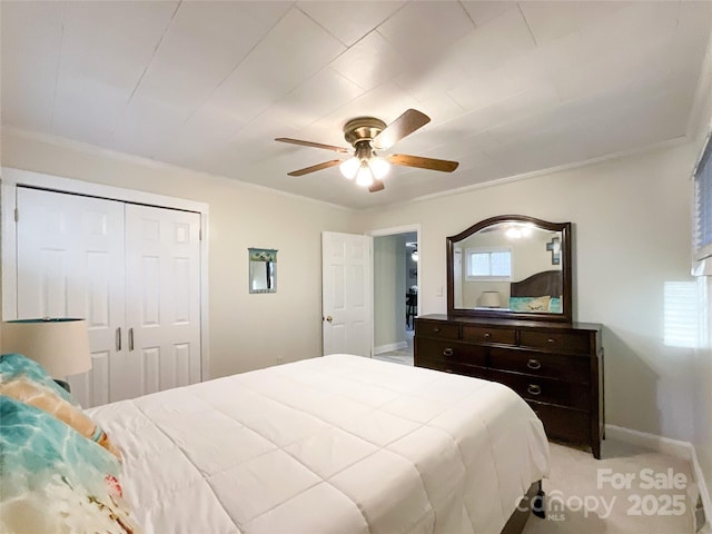 bedroom with a closet, crown molding, ceiling fan, and light colored carpet