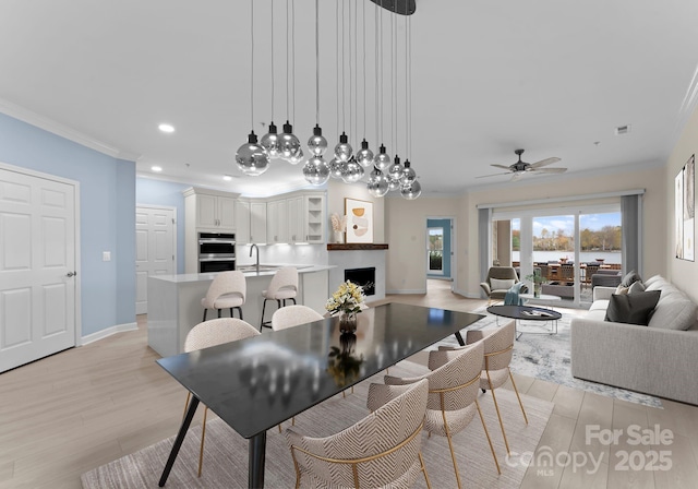 dining room featuring ceiling fan, crown molding, and light wood-type flooring