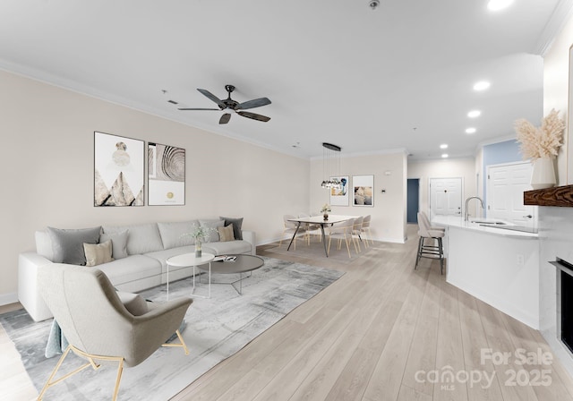 living room featuring ceiling fan, light wood-type flooring, and ornamental molding