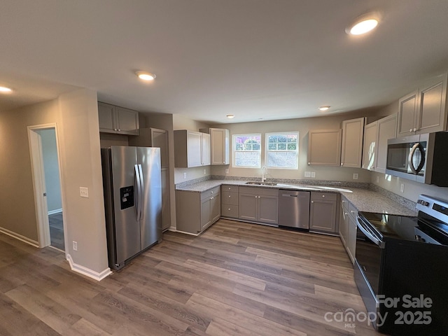 kitchen featuring gray cabinets, sink, stainless steel appliances, and hardwood / wood-style flooring