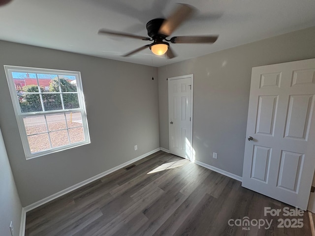 unfurnished bedroom featuring ceiling fan and dark wood-type flooring