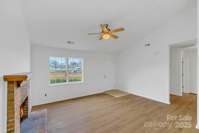 unfurnished living room featuring ceiling fan, a fireplace, vaulted ceiling, and light wood-type flooring