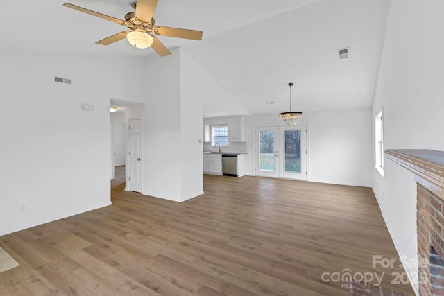 unfurnished living room featuring hardwood / wood-style floors, ceiling fan, french doors, high vaulted ceiling, and sink