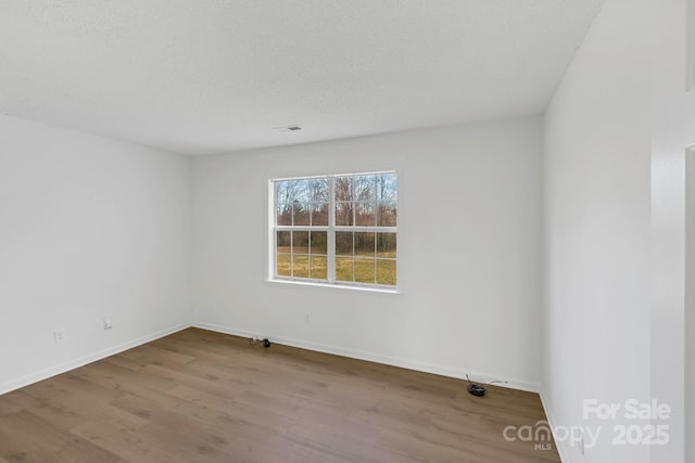 unfurnished room with hardwood / wood-style floors and a textured ceiling