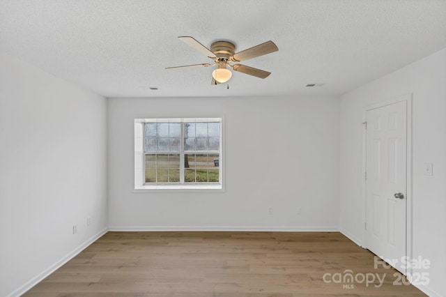 empty room featuring ceiling fan, light wood-type flooring, and a textured ceiling