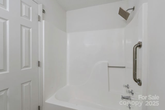 bathroom with a textured ceiling and shower / bath combination