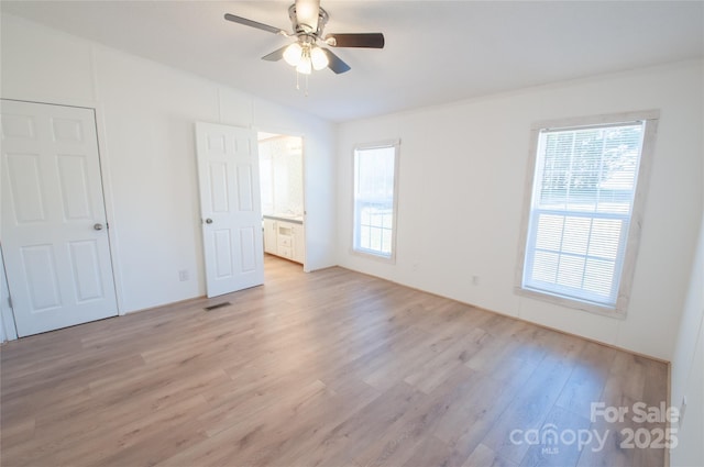 unfurnished bedroom with ceiling fan, connected bathroom, and light hardwood / wood-style flooring