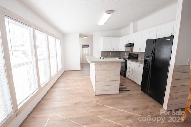 kitchen with a textured ceiling, sink, black appliances, white cabinets, and a kitchen island