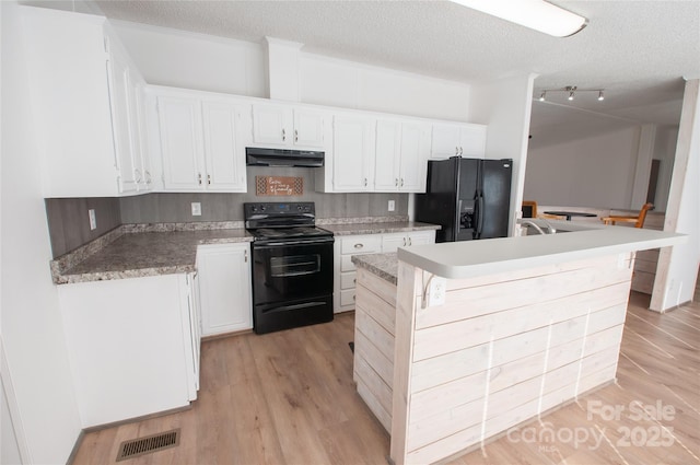 kitchen featuring a center island, black appliances, white cabinets, a textured ceiling, and a kitchen bar