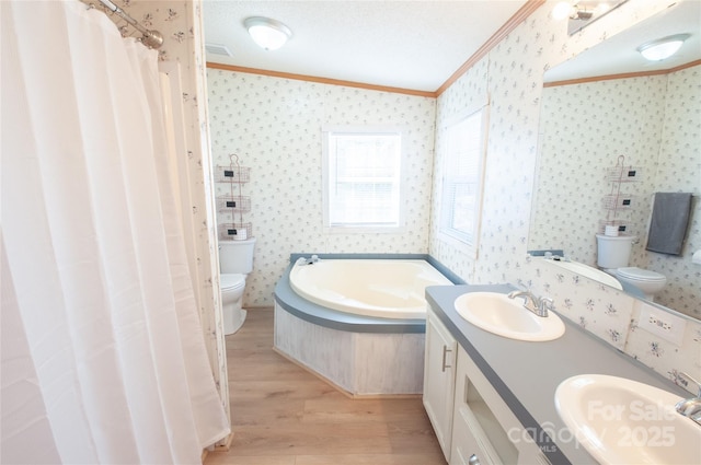 bathroom featuring ornamental molding, a washtub, a textured ceiling, hardwood / wood-style floors, and toilet