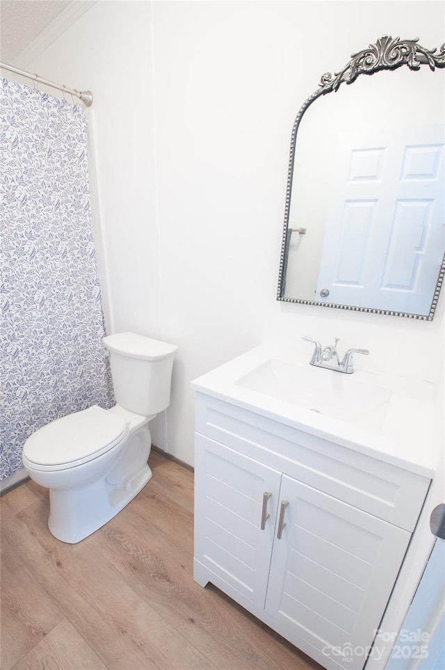 bathroom with vanity, crown molding, hardwood / wood-style flooring, toilet, and curtained shower