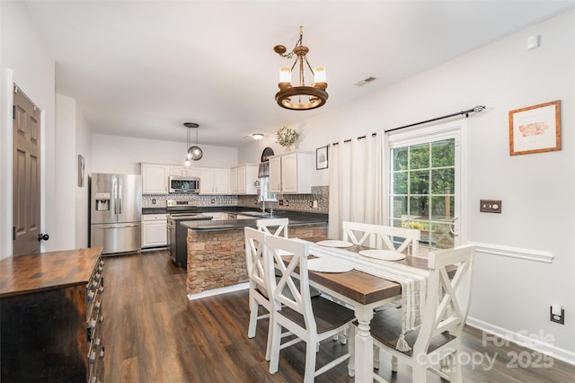 dining area with dark hardwood / wood-style flooring, an inviting chandelier, and sink