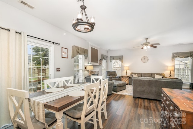 dining space featuring ceiling fan with notable chandelier and dark hardwood / wood-style floors