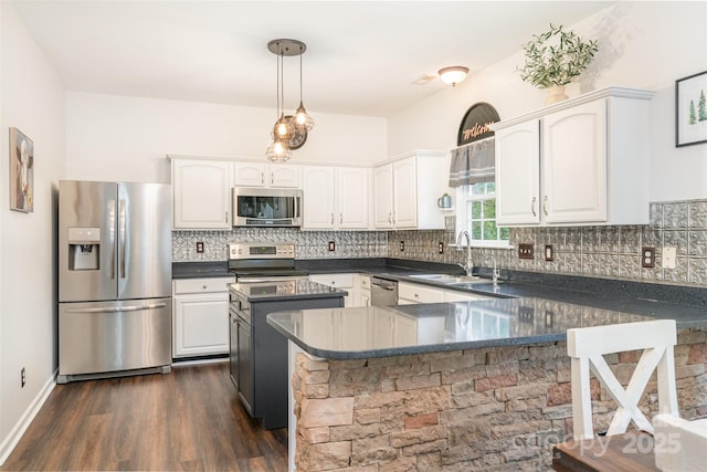 kitchen with white cabinets, hanging light fixtures, sink, dark hardwood / wood-style floors, and appliances with stainless steel finishes