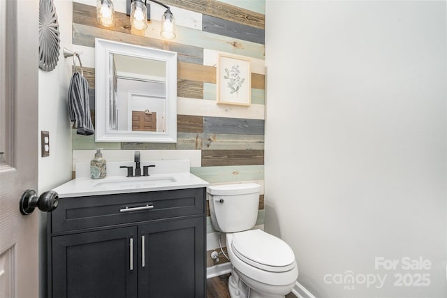 bathroom featuring wooden walls, vanity, and toilet