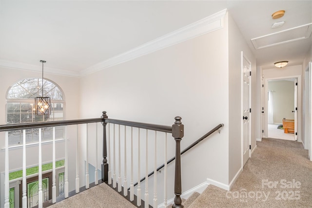 hall featuring light colored carpet, crown molding, and a notable chandelier