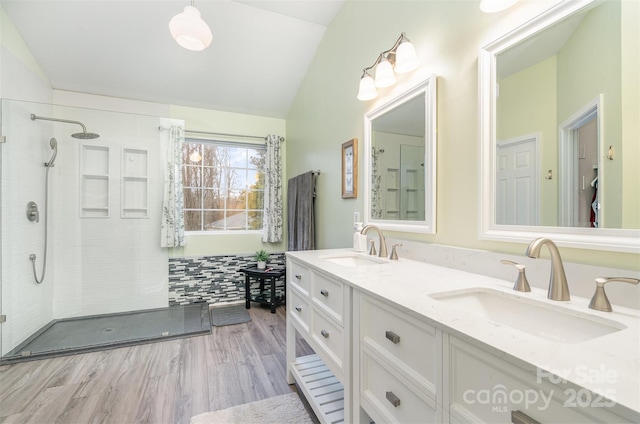 bathroom with tiled shower, vanity, hardwood / wood-style flooring, and vaulted ceiling