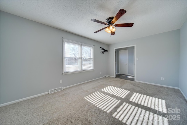 carpeted empty room featuring ceiling fan and a textured ceiling