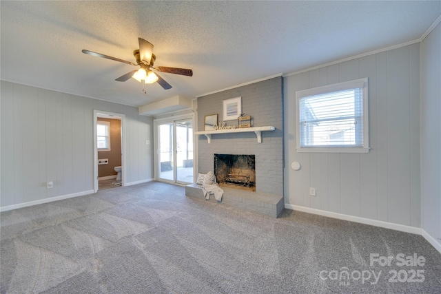 unfurnished living room featuring ceiling fan, a fireplace, carpet, and crown molding