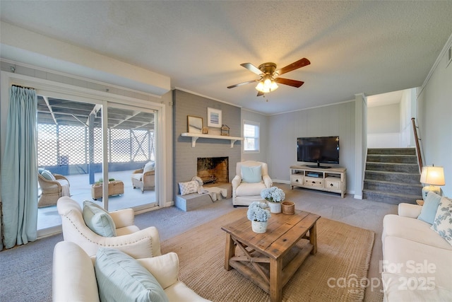 carpeted living room featuring ceiling fan, a healthy amount of sunlight, ornamental molding, and a brick fireplace