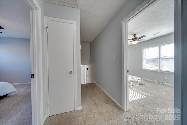 corridor featuring light carpet and a textured ceiling