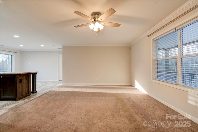 carpeted spare room with ceiling fan and crown molding