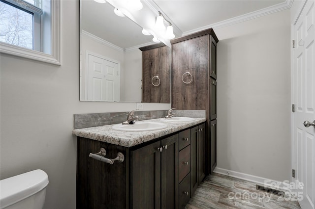 bathroom with wood-type flooring, vanity, toilet, and crown molding