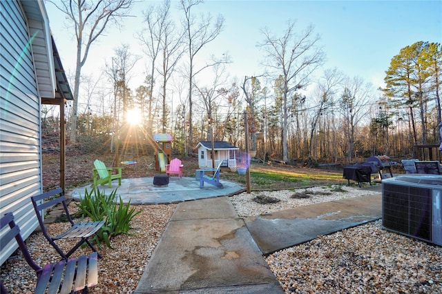 view of patio / terrace with central air condition unit, a playground, and a storage unit