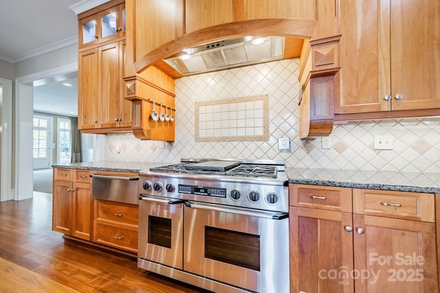 kitchen with stone counters, tasteful backsplash, crown molding, range with two ovens, and custom exhaust hood