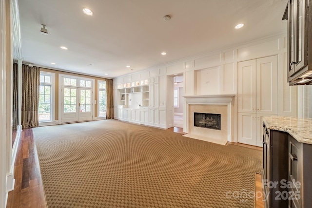 unfurnished living room featuring crown molding, a high end fireplace, and dark colored carpet