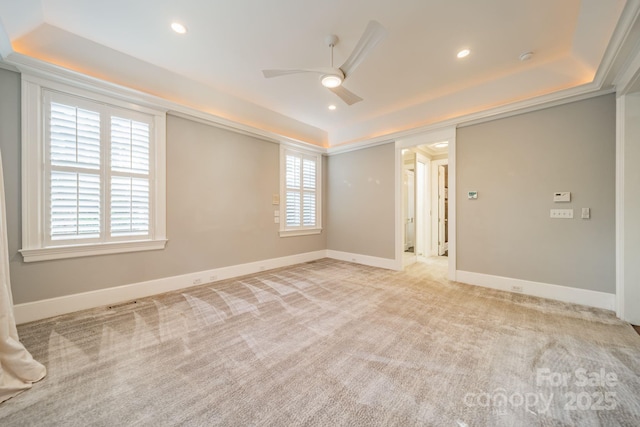 carpeted spare room featuring a raised ceiling and ceiling fan