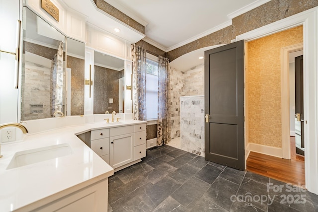 bathroom with vanity, ornamental molding, and tiled shower