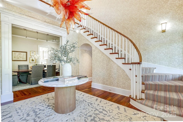 1333 Carlton Ave, Charlotte, NC 28203 - stairs featuring arched walkways, wallpapered walls, hardwood / wood-style floors, and baseboards