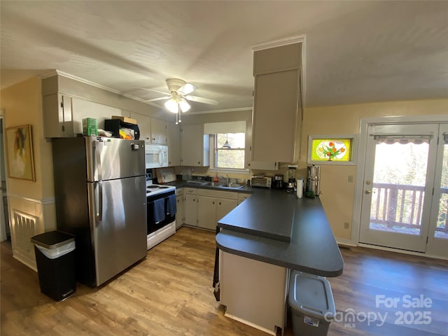 kitchen with sink, white appliances, light wood-type flooring, ceiling fan, and kitchen peninsula