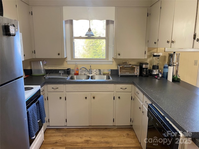 kitchen with dishwasher, range with electric cooktop, stainless steel fridge, sink, and white cabinetry